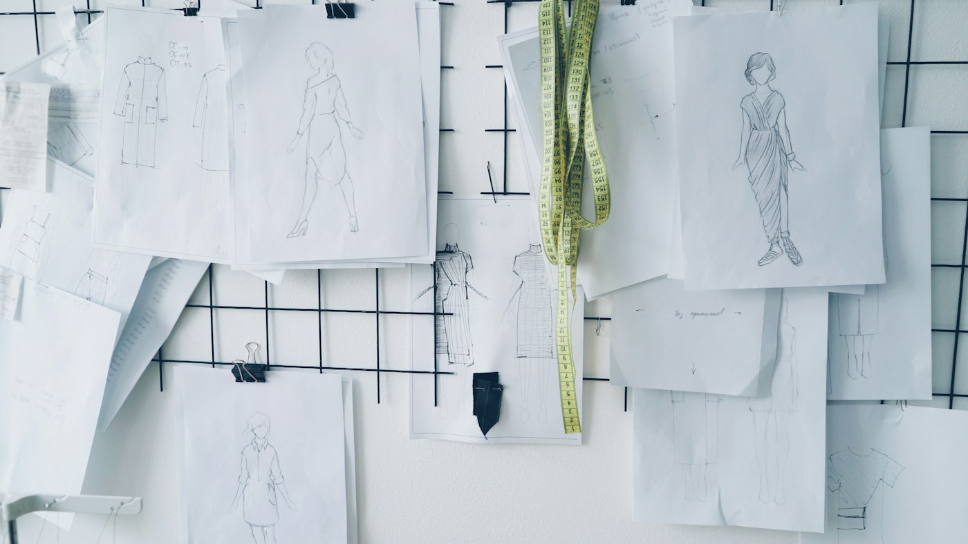 Disegni di capi di abbigliamento appesi a una parete con un metro da sarta