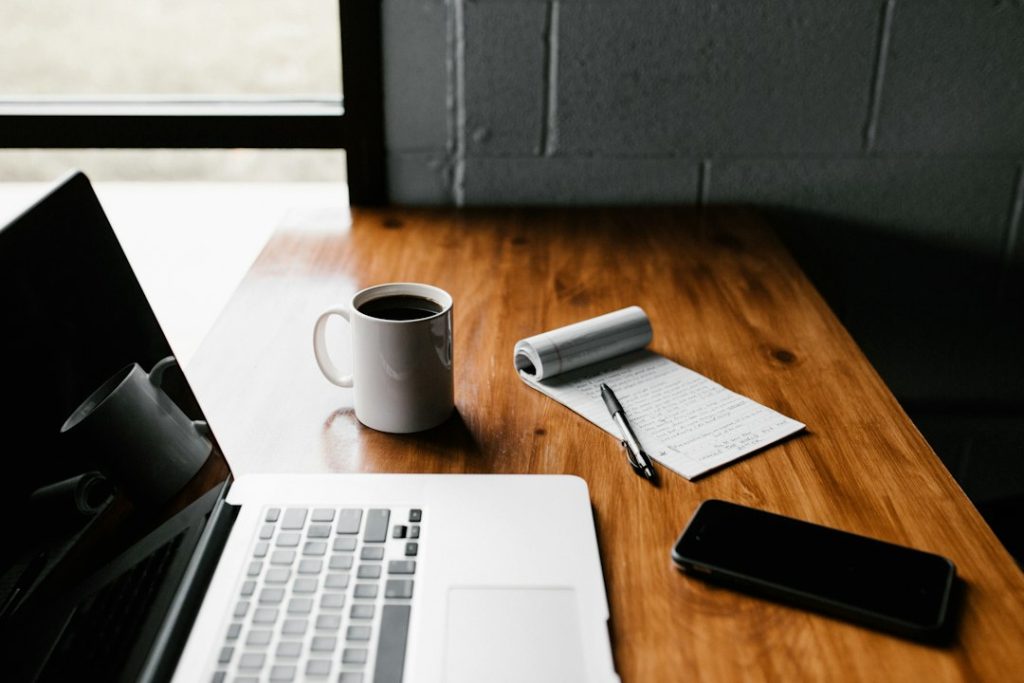 Computer portatile, blocco per appunti e penna su un tavolo di lavoro